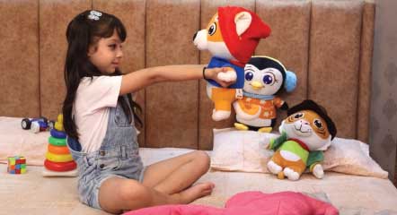 Girl Child playing with dog, tiger and penguin plush toys on a bed
