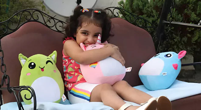 Child sitting on a swing with plush toys in a garden setting